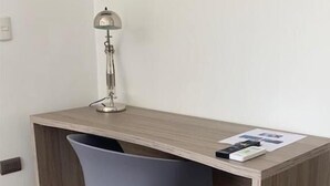 Un bureau moderne avec une chaise grise, une lampe de bureau et quelques feuilles de papier.