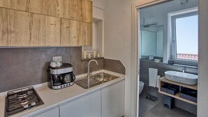 A compact kitchen with a coffee maker, a sink, and wooden cabinets. - Olive House, luxury retreat (furore)