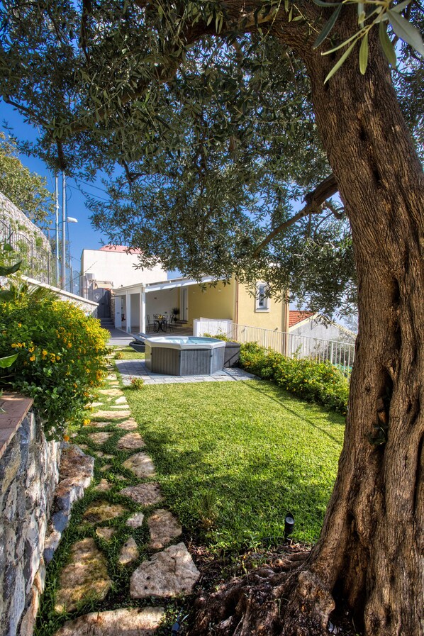 A garden with a hot tub, stone pathway, and a tree.