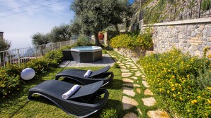 Un giardino con idromassaggio, poltrone relax e un muro in pietra.