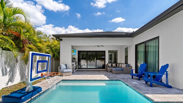 A swimming pool with a basketball hoop, outdoor seating, and a view of the house. - The Blue Heron | Heated Pool and Outdoor Grill | Near Beach (Naples)