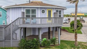 Una casa de dos pisos con un balcón, una puerta principal y un pequeño porche.