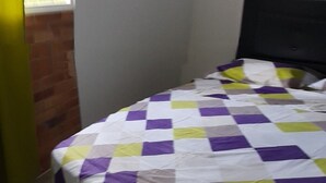 Een slaapkamer met een bed, een raam en uitzicht op groen.