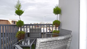 A balcony with wicker furniture, a metal railing, and potted plants. - VIP Church Street Apartments (Craigavon)