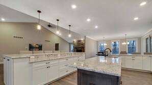 A spacious kitchen with a large island, white cabinetry, and a stone accent wall.
