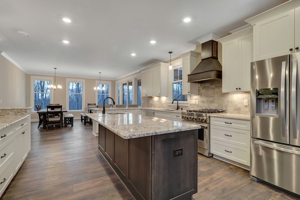 A spacious kitchen with a large island, stainless steel appliances, and ample natural light from large windows.