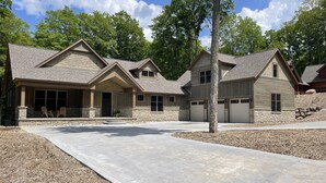 A modern residential building with a stone facade, multiple garage doors, and a spacious driveway.