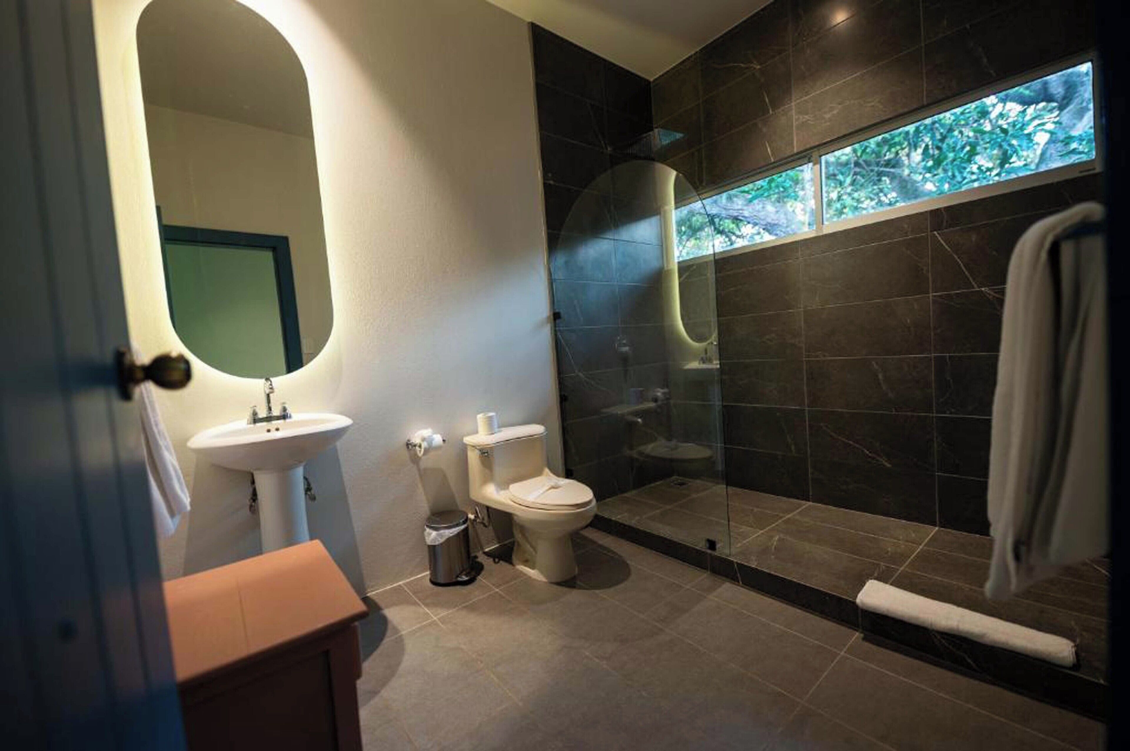A modern bathroom with a glass-enclosed shower, a white sink, and a toilet.