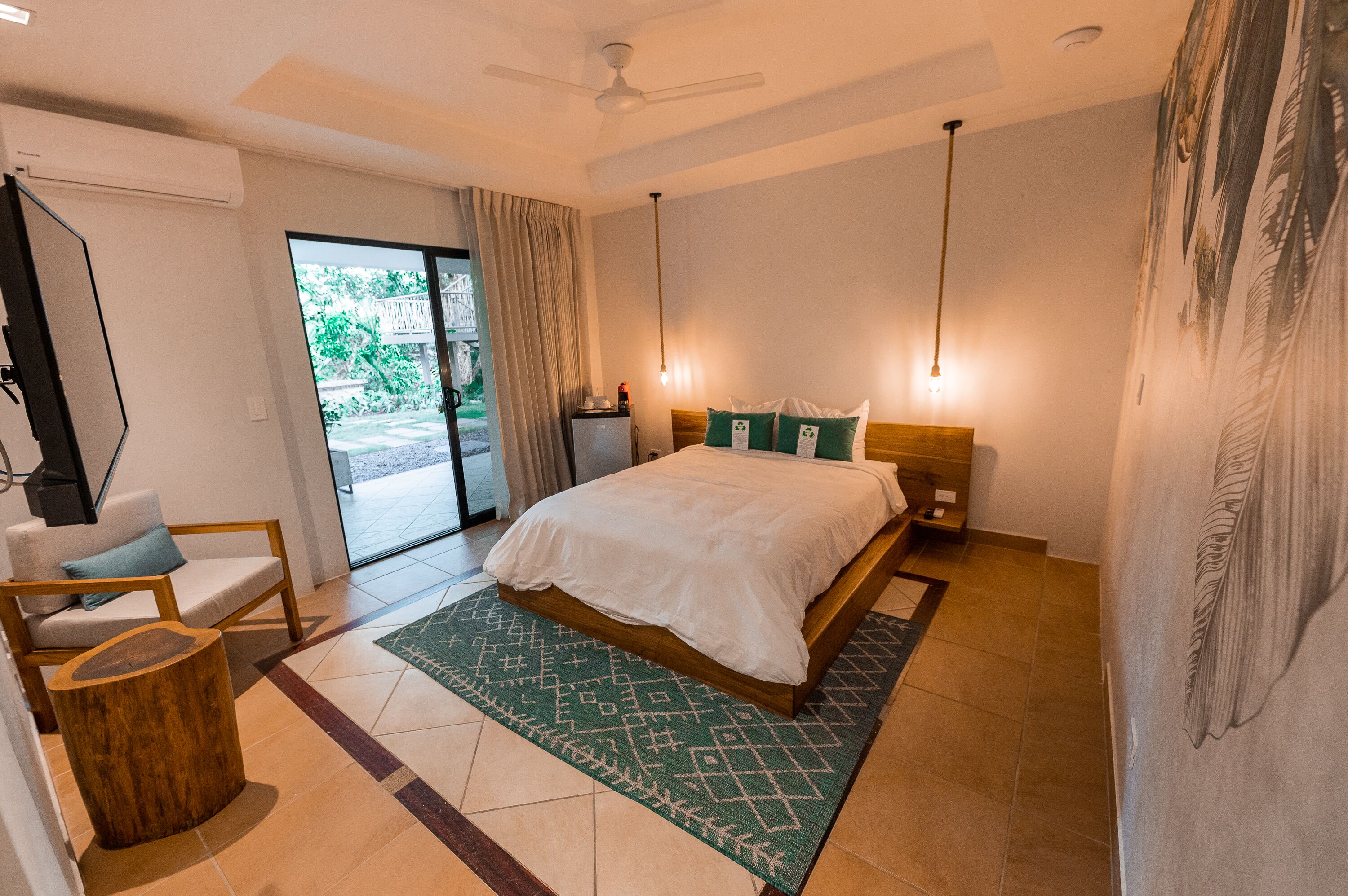Un dormitorio moderno con una cama, una silla, un escritorio y un ventanal grande.