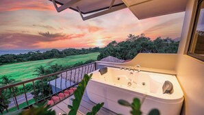 Balcón con hidromasaje con vista a un paisaje verde y un atardecer.