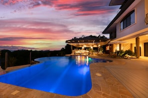 A swimming pool with a sunset view, a covered outdoor seating area, and a modern house. - Marala Hotel (Parrita)