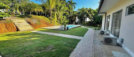 A modern house with a well-maintained lawn, a swimming pool, and a staircase leading to a higher elevation.