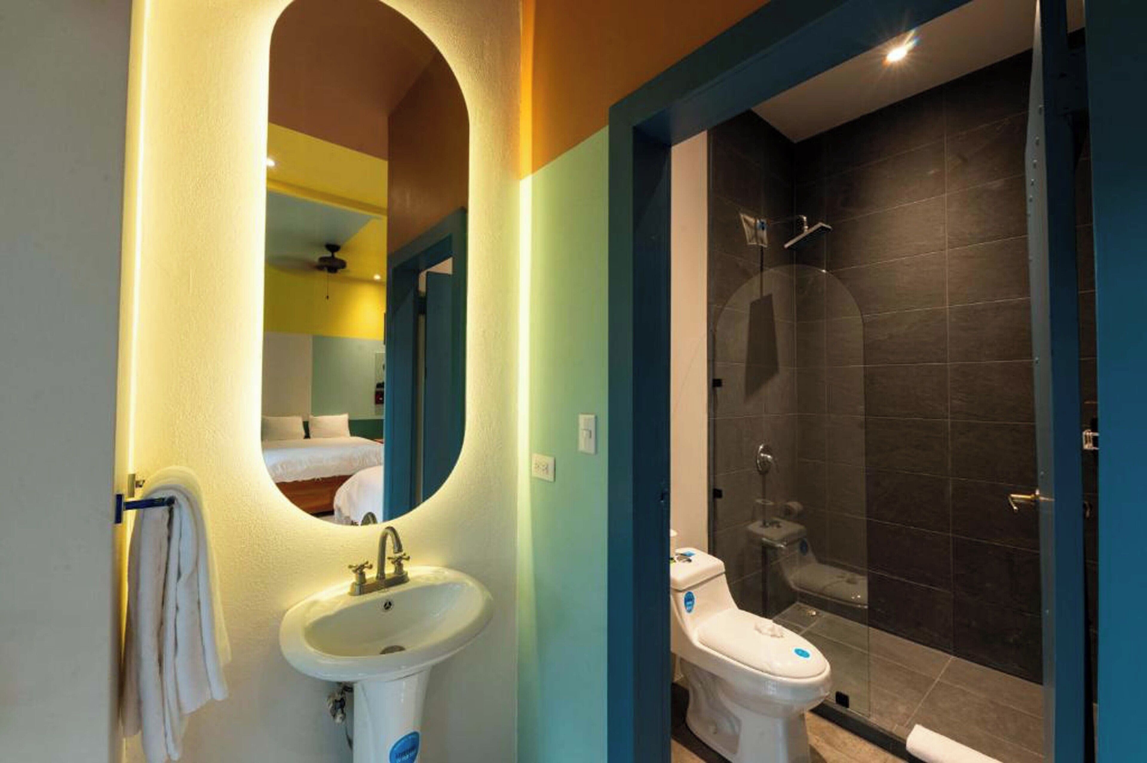 A bathroom with a sink, mirror, and shower area.