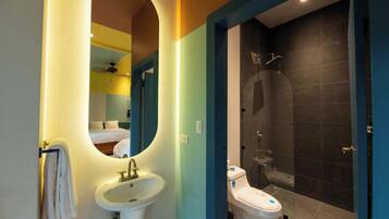 A bathroom with a sink, mirror, and shower area.