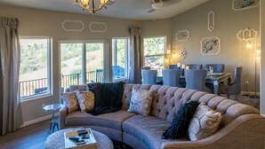 A spacious living room with a large sectional sofa, a round ottoman, and a dining area with a table and chairs. - Prescott Perfection,  elegant 3 bedroom home (Prescott)