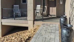 A covered outdoor area with a concrete floor, two white rocking chairs, and a metal railing. - Prescott Perfection,  elegant 3 bedroom home (Prescott)