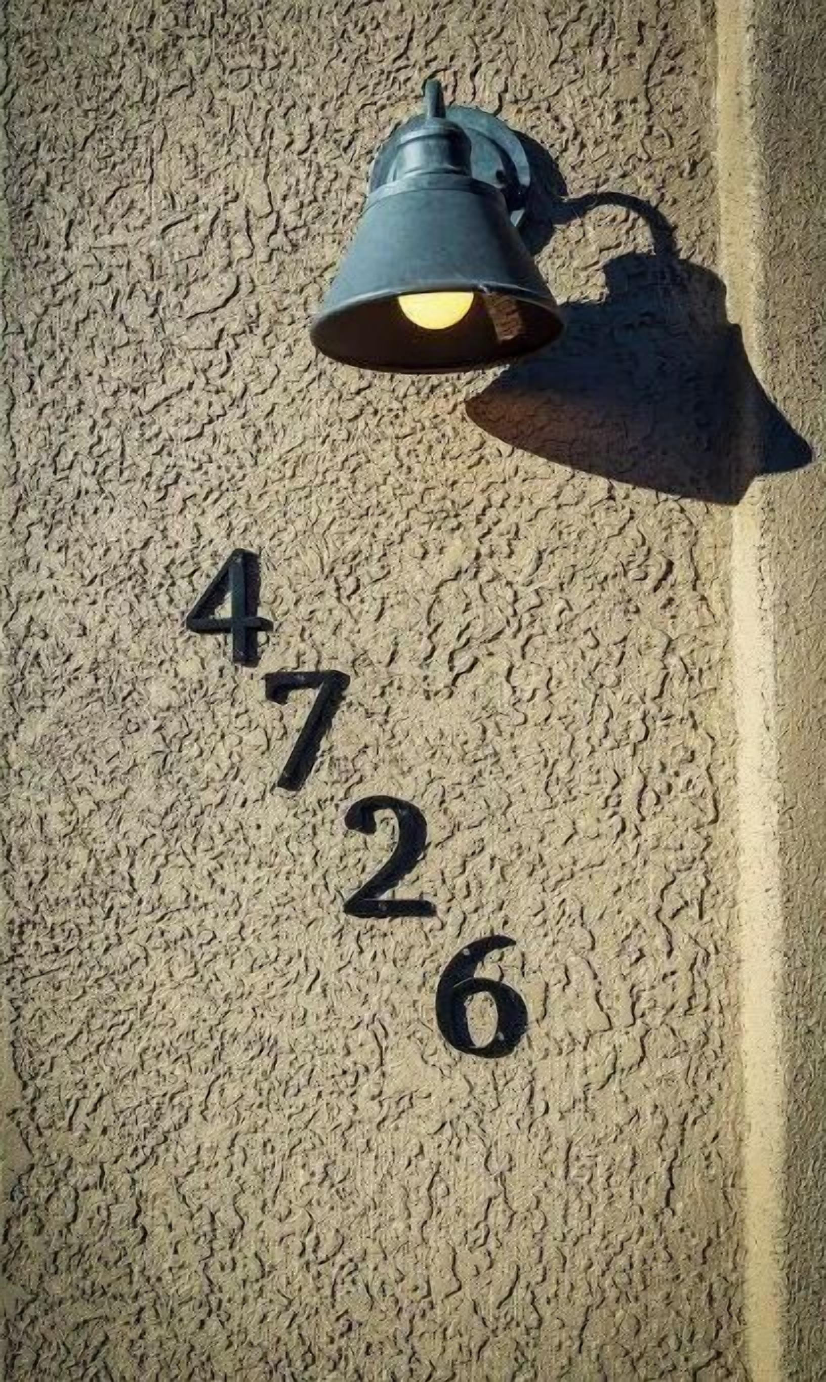 Número 4726 en una pared texturizada, con una lámpara de pared encima.