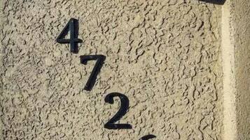 Número 4726 en una pared texturizada, con una lámpara de pared encima.