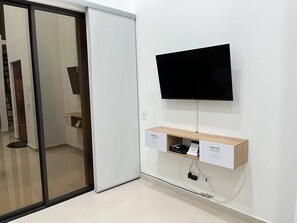 A modern room with a sliding door, a mounted TV, and a wooden shelf with a drawer.