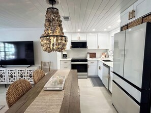 A modern kitchen with white cabinetry, a central island, and a chandelier.