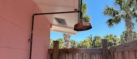 Un luminaire extérieur en métal, fixé au mur extérieur d’un bâtiment, avec une clôture en bois en arrière-plan.