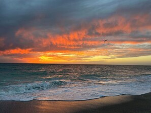 A beach with waves and a sunset.