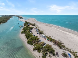 Vista aérea de una zona costera con playa, puerto deportivo y aparcamiento.