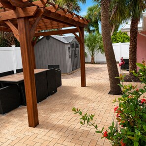 Un patio con pérgola, mobiliario exterior y un pequeño cobertizo.