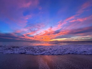 A beach with waves and a sunset.