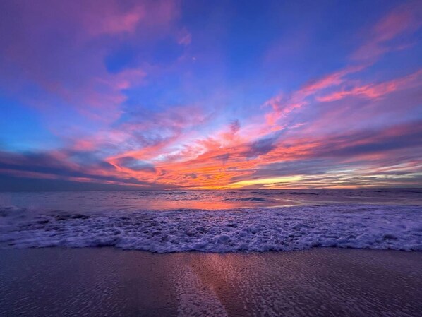 Una playa con olas y un atardecer.