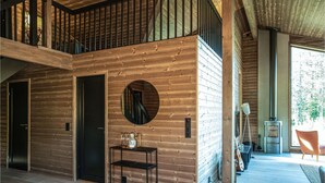 A wooden interior with a staircase, a round mirror, a small table, and a view of a room with a fireplace and a chair. - Beautiful home in Steinsholt with sauna (Steinsholt)