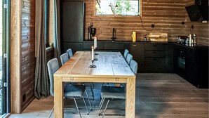 A wooden interior with a dining table, chairs, a window, and a kitchen area. - Beautiful home in Steinsholt with sauna (Steinsholt)