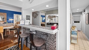 A modern kitchen with a bar area, wooden chairs, and a dining table. - Beautiful Spacious Home in Palmetto Dunes w Pool 5 minute Walk to the Beach ! (Hilton Head Island)