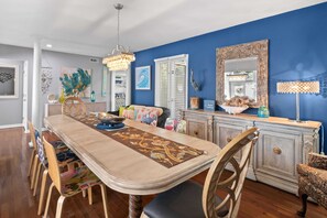 A dining area with a long table, chairs, and a decorative runner. There is a chandelier above the table and a mirror on the wall. - Beautiful Spacious Home in Palmetto Dunes w Pool 5 minute Walk to the Beach ! (Hilton Head Island)