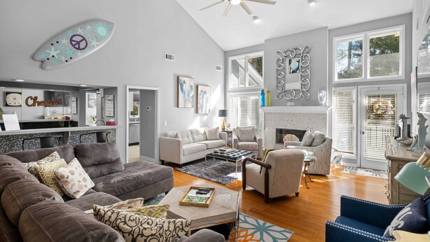 A spacious living room with a fireplace, modern furniture, and a ceiling fan. - Beautiful Spacious Home in Palmetto Dunes w Pool 5 minute Walk to the Beach ! (Hilton Head Island)