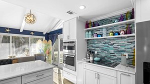 A modern kitchen with white cabinetry, a glass backsplash, and a central island. - Beautiful Spacious Home in Palmetto Dunes w Pool 5 minute Walk to the Beach ! (Hilton Head Island)