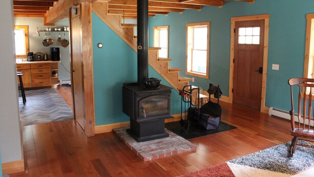Un intérieur en bois avec une cheminée, un coin cuisine et un escalier.
