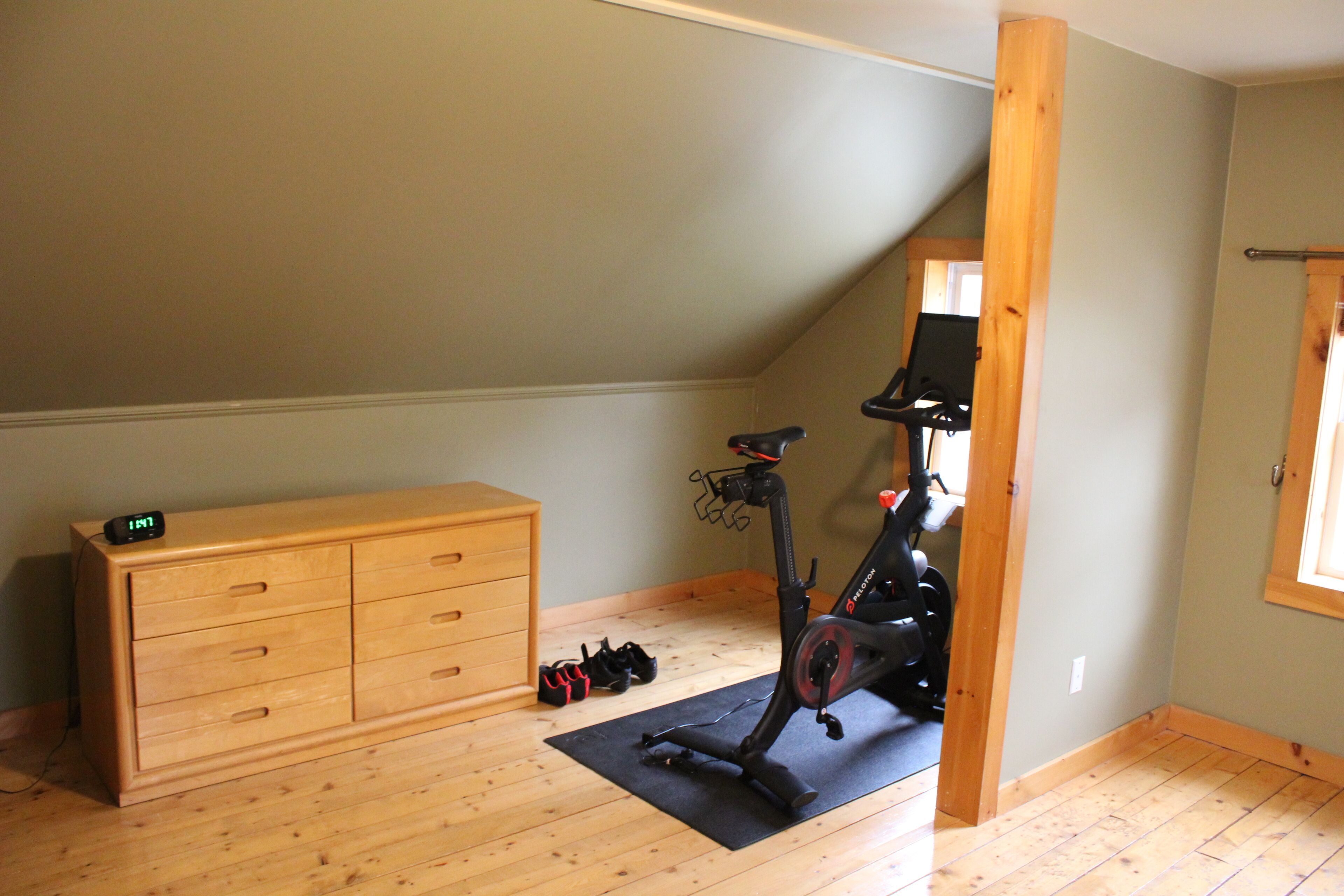 A room with a wooden dresser, an exercise bike, and a mat on the floor.