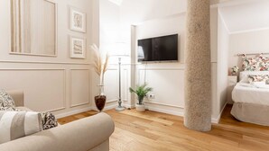 A modern living room with a sofa, a television, a decorative vase, and a column. - Hostmate - Milano - Ticinese (Milano)