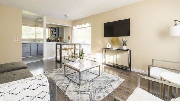 A modern living room with a sofa, a coffee table, and a TV mounted on the wall.