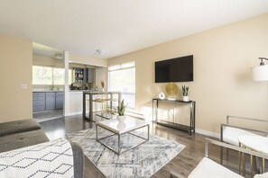 A modern living room with a sofa, a coffee table, and a TV mounted on the wall. - Walkable condo in heart of vibrant D/n Redmond,  m/s from Microsoft, woodinville (Redmond)