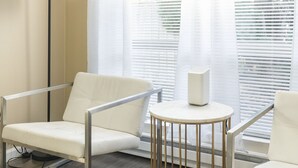 A modern room with two white leather chairs, a round table, and a floor lamp.
