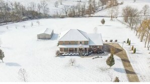 A large house with a covered porch and a garage, surrounded by snow-covered ground and sparse trees. - Beautiful farm stay apartment, rural Georgetown KY (Georgetown)