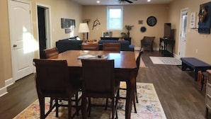 A spacious living room with a large wooden dining table, dark chairs, a sofa, and a television. - Beautiful farm stay apartment, rural Georgetown KY (Georgetown)