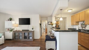 Uma cozinha moderna com armários de madeira, uma ilha central e uma área de refeições com uma mesa e cadeiras brancas.