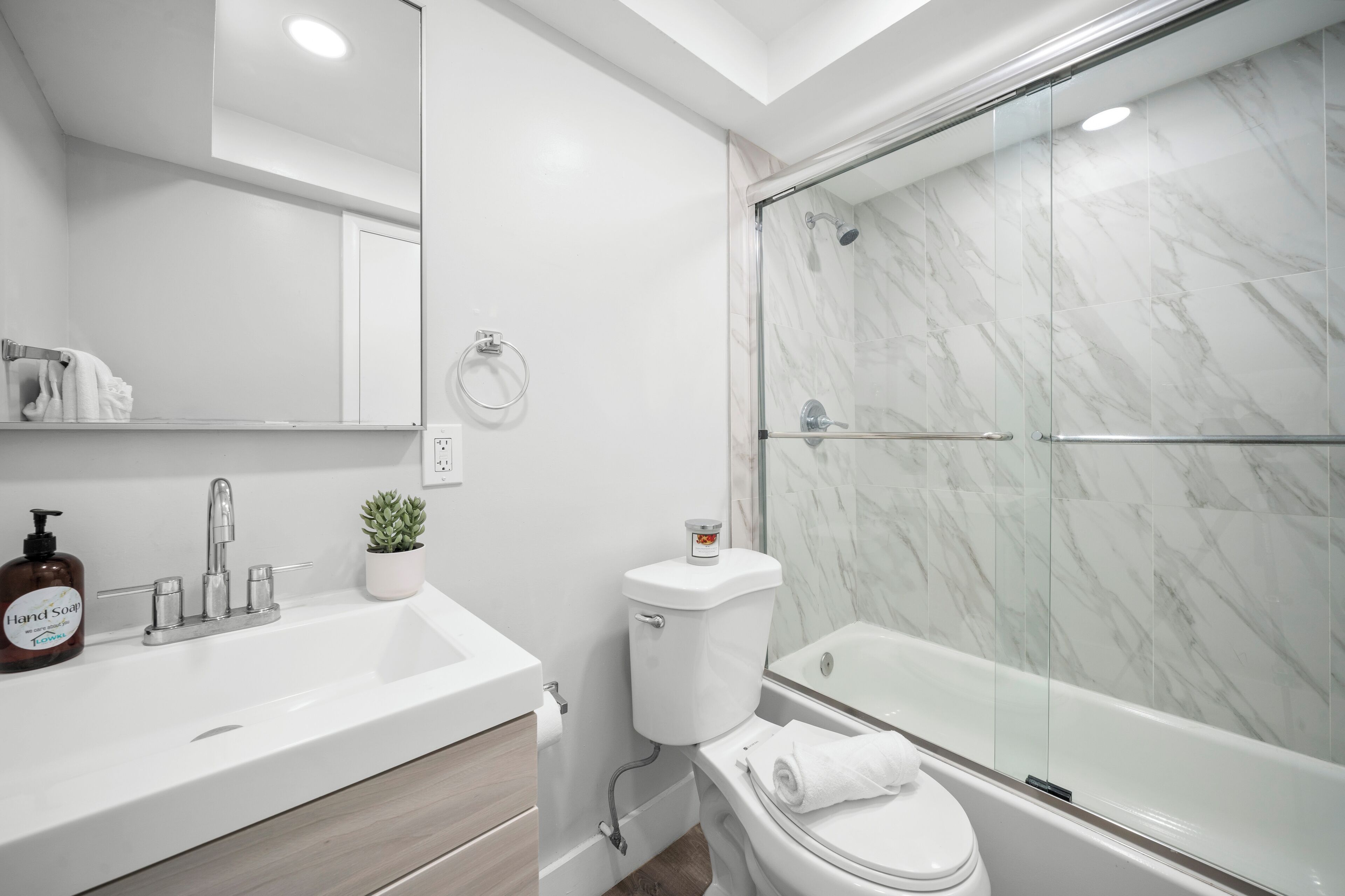 A modern bathroom with a white sink, a toilet, and a glass-enclosed shower.