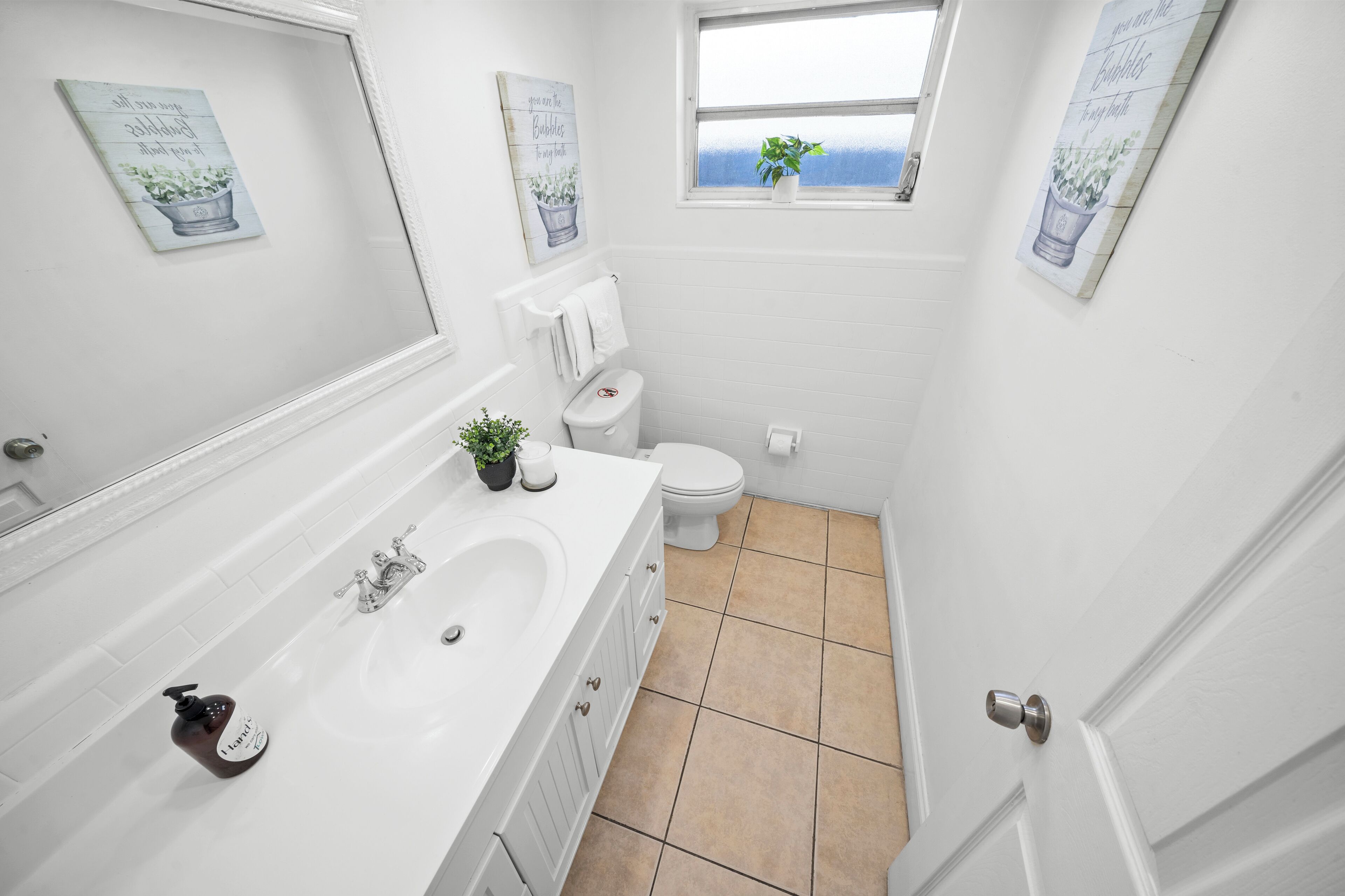 Une petite salle de bain blanche, avec une baignoire, des toilettes et une fenêtre donnant sur un beau paysage.