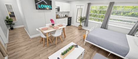 Una habitación moderna y bien iluminada con una cama, un comedor y una cocina.