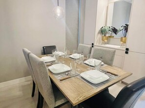Una mesa de comedor con platos, vasos y cubiertos, rodeada de sillas.