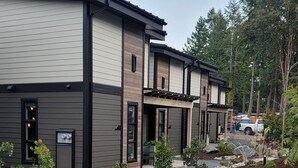 Ett modernt hus i två våningar med en välskött gräsmatta och trädgård.